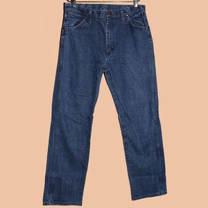 K&ouml;nnte beinhalten: Eine dunkelblaue Jeanshose mit klassischer gerader Passform. Die Jeans hat einen Knopfverschluss und G&uuml;rtelschlaufen.
