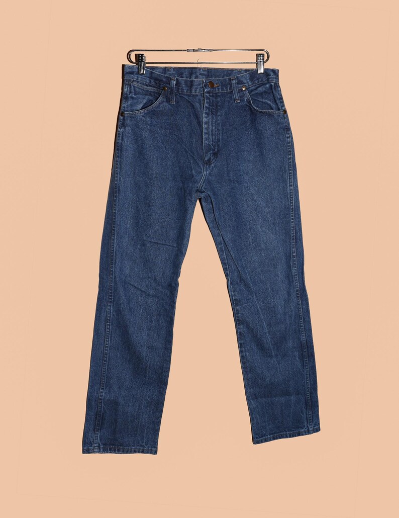 K&ouml;nnte beinhalten: Eine dunkelblaue Jeanshose mit klassischer gerader Passform. Die Jeans hat einen Knopfverschluss und G&uuml;rtelschlaufen.