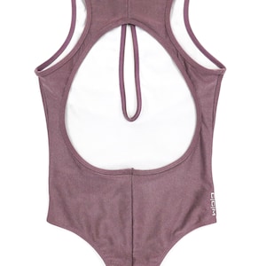 size small lilac bodysuit showing off the back with high crew neckline, large eyelet, sleeveless, open back, can be worn as a bodysuit, one piece swimsuit, and gym suit