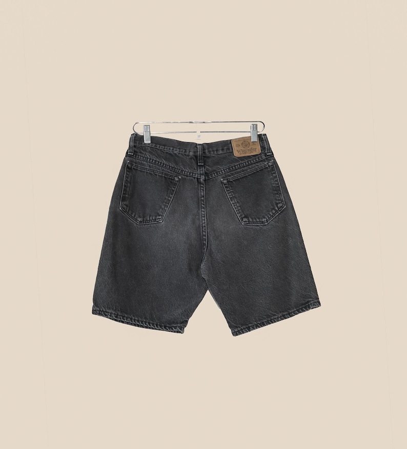 May include: Black denim shorts with a brown leather patch on the back pocket that says "Wrangler".