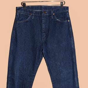 May include: A pair of dark blue denim jeans with a classic straight leg fit. The jeans have a button fly and belt loops.