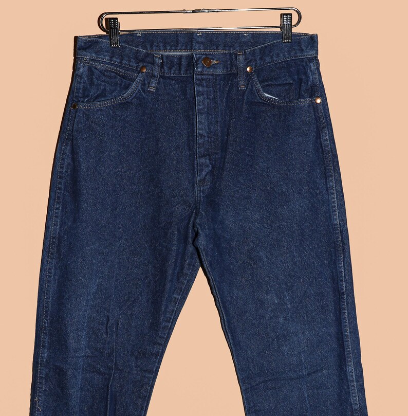 May include: A pair of dark blue denim jeans with a classic straight leg fit. The jeans have a button fly and belt loops.