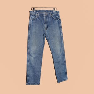 May include: A pair of blue denim jeans with a straight leg fit. The jeans have a classic five-pocket style and a button fly.