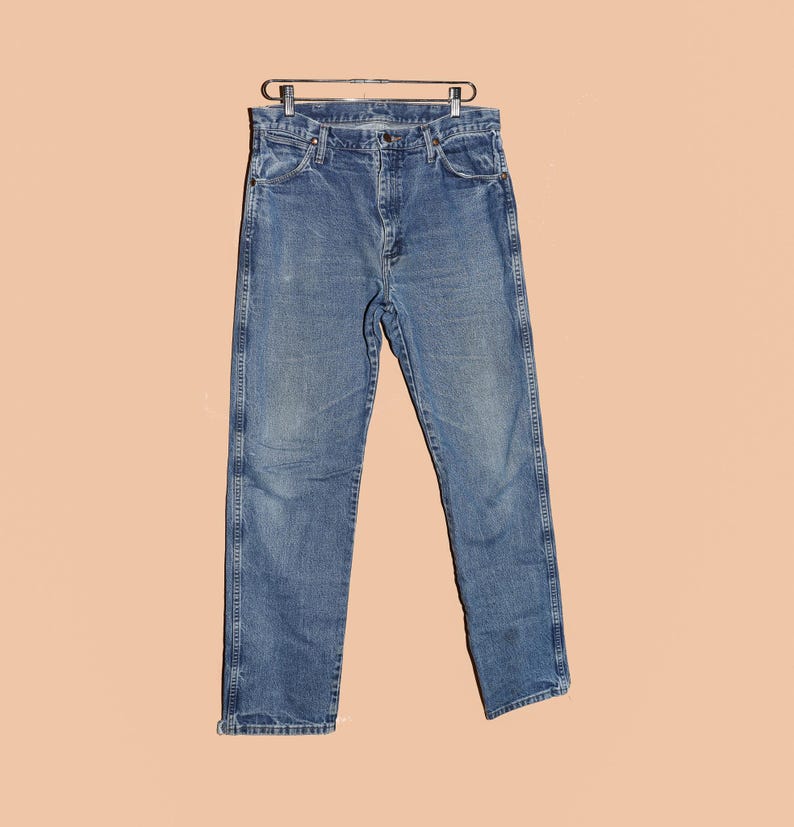 May include: A pair of blue denim jeans with a straight leg fit. The jeans have a classic five-pocket style and a button fly.