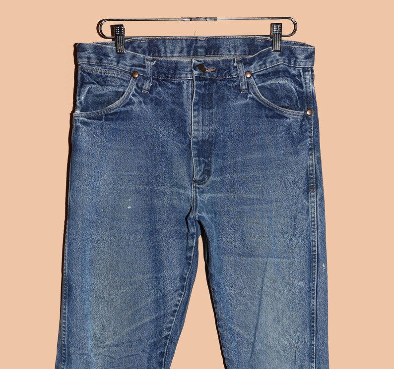 Pu&ograve; includere: Un paio di jeans blu denim con una vestibilit&agrave; classica a gamba dritta. I jeans hanno un lavaggio chiaro e sono leggermente sbiaditi.