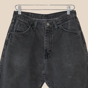 May include: A pair of black denim jeans with a classic five-pocket style. The jeans have a straight leg and a relaxed fit.