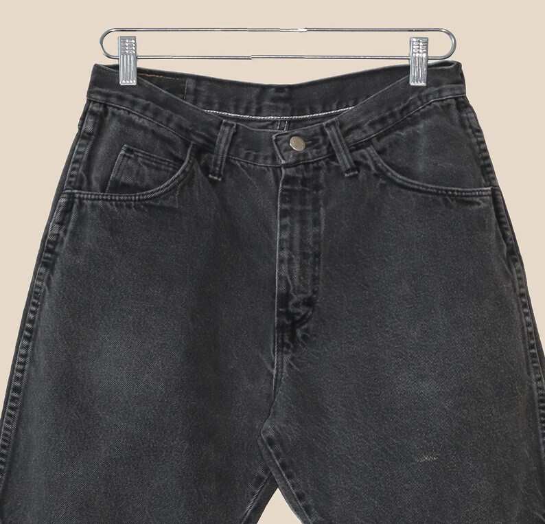 May include: A pair of black denim jeans with a classic five-pocket style. The jeans have a straight leg and a relaxed fit.