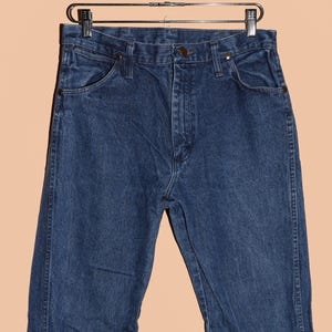 K&ouml;nnte beinhalten: Eine dunkelblaue Jeanshose im klassischen 5-Pocket-Stil. Die Jeans hat einen geraden Schnitt und einen Knopfverschluss.
