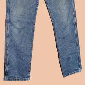 May include: A pair of blue denim jeans with a straight leg fit. The jeans have a faded wash and are made of a soft, comfortable fabric.