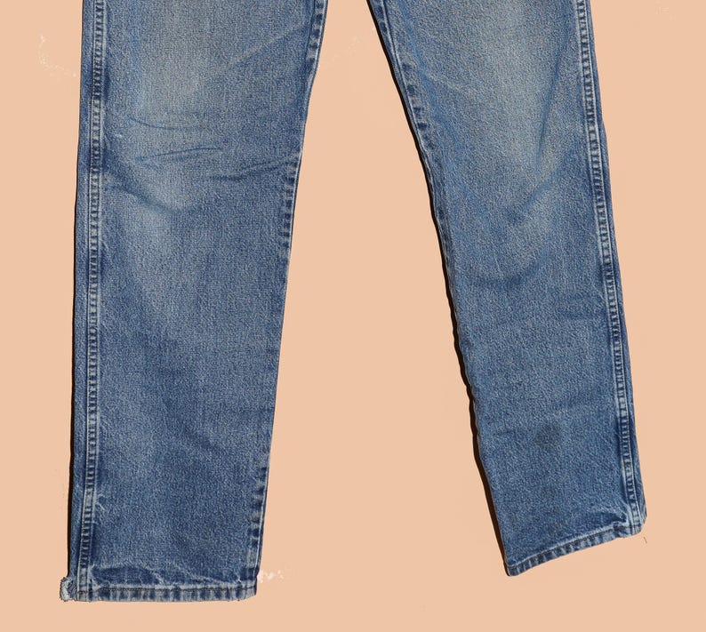May include: A pair of blue denim jeans with a straight leg fit. The jeans have a faded wash and are made of a soft, comfortable fabric.