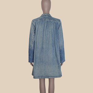 May include: A light blue denim shirt dress with long sleeves and a button-up front.
