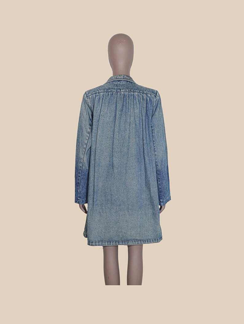 May include: A light blue denim shirt dress with long sleeves and a button-up front.