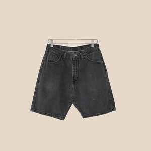 May include: Black denim shorts with a button and zipper closure. The shorts have five pockets and a relaxed fit.