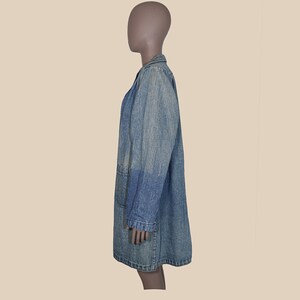 May include: A long denim jacket with a collar and long sleeves. The jacket is a light blue color and has a faded look.