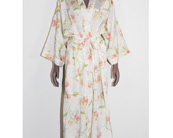 May include: A cream-colored floral kimono-style robe with a tie waist. The robe features a V-neck and wide sleeves. The floral pattern includes pink and orange flowers with green leaves. The robe is displayed on a mannequin.
