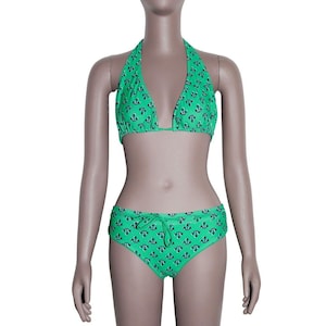 Peut inclure: Ensemble de bikini vert avec motif d'ancres noires. Le haut est un modèle à nouer autour du cou et dans le dos, et le bas a une taille à cordon. L'ensemble est présenté sur un mannequin.
