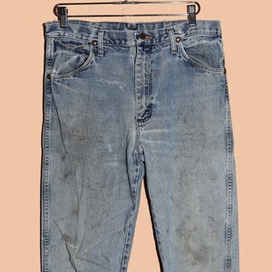 May include: Light blue denim jeans with a faded and worn look. The jeans have a classic five-pocket style and a straight leg.