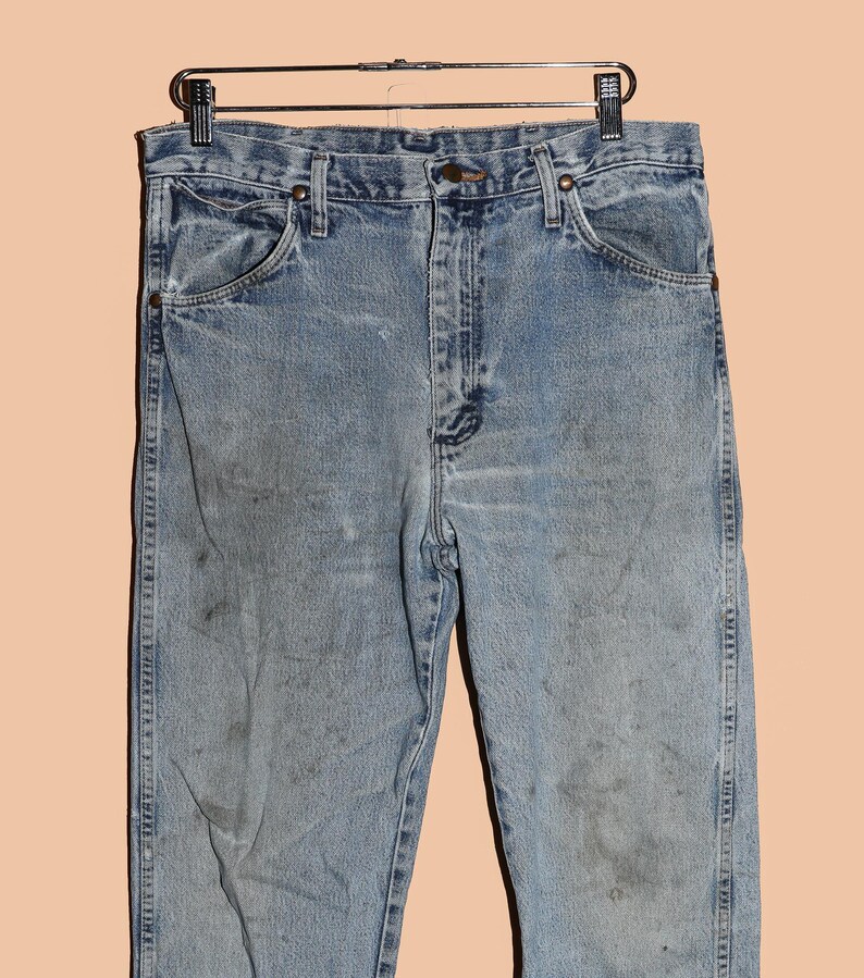 May include: Light blue denim jeans with a faded and worn look. The jeans have a classic five-pocket style and a straight leg.