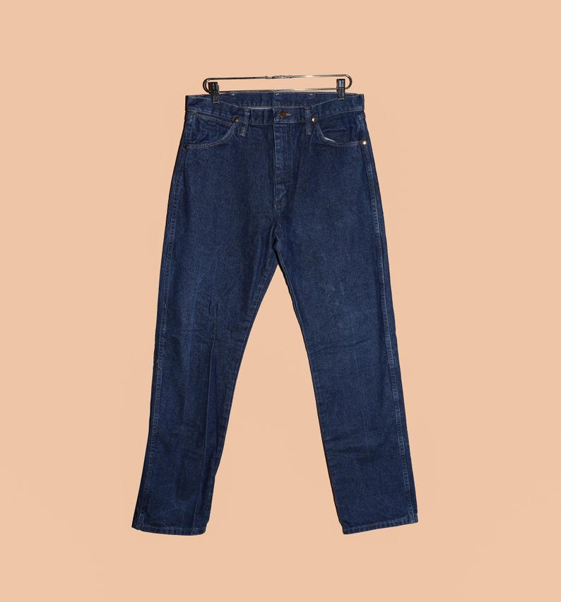 May include: A pair of dark blue denim jeans with a button fly and belt loops.
