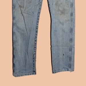 May include: A pair of light blue denim jeans with faded areas and visible stitching. The jeans have a straight leg and a classic fit.