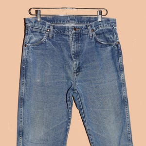 May include: A pair of light blue denim jeans with a classic straight leg fit. The jeans have a faded look and are made of a soft, comfortable cotton blend.