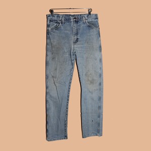 May include: A pair of light blue denim jeans with a faded look. The jeans have a straight leg and a classic five-pocket style.