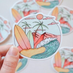 May include: A sticker with a beach scene featuring two palm trees, a red mountain, a blue wave, and two surfboards. The sticker is on a white background.
