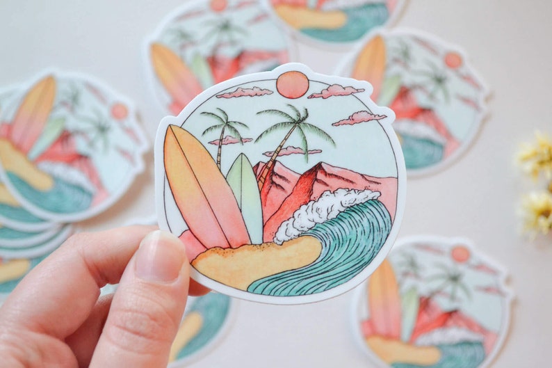 May include: A sticker with a beach scene featuring two palm trees, a red mountain, a blue wave, and two surfboards. The sticker is on a white background.