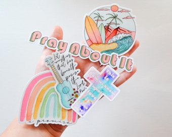 May include: A set of five stickers with various designs and inspirational quotes. The stickers feature a rainbow, a ukulele, a cross, a beach scene, and the phrase "Pray About It".