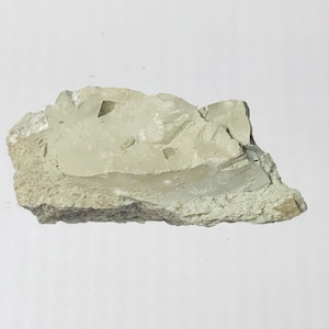 May include: A rough, light green rock with several small, clear crystals embedded in it.