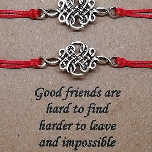 May include: Two red string bracelets with silver knot charms. The bracelets are tied together with a message that reads "Soul Sister". The text below the bracelets reads "Good friends are hard to find, harder to leave and impossible to forget."