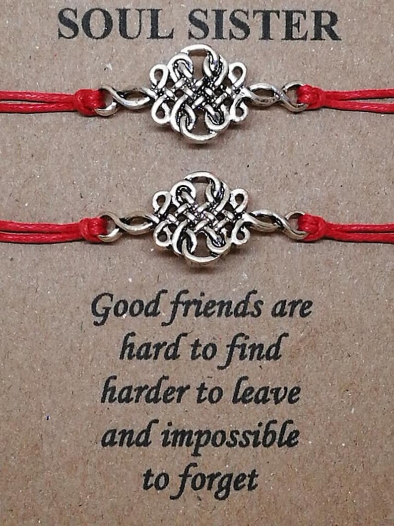 May include: Two red string bracelets with silver knot charms. The bracelets are tied together with a message that reads "Soul Sister". The text below the bracelets reads "Good friends are hard to find, harder to leave and impossible to forget."
