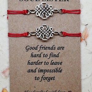 May include: Two red string bracelets with silver knot charms. The card reads "Soul Sister" and "Good friends are hard to find, harder to leave and impossible to forget. Handcrafted with love."