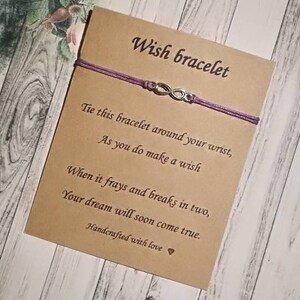 Puede incluir: Un brazalete de la suerte morado con un dije de infinito y una tarjeta que dice "Wish bracelet". La tarjeta también incluye instrucciones sobre cómo hacer un deseo con el brazalete. La tarjeta dice: "Ata este brazalete alrededor de tu muñeca, Mientras haces un deseo Cuando se deshilache y se rompa en dos, Tu sueño pronto se hará realidad. Hecho a mano con amor"