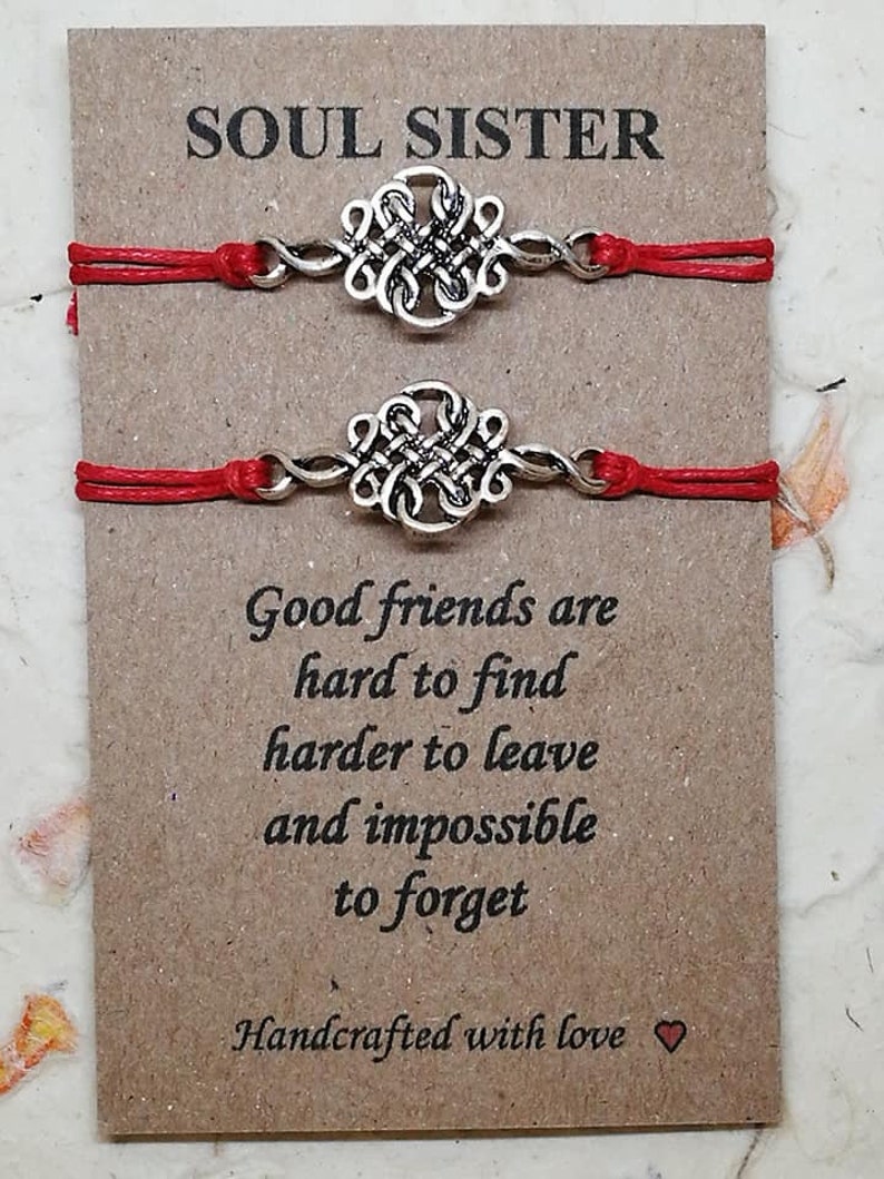 May include: Two red string bracelets with silver knot charms. The card reads "Soul Sister" and "Good friends are hard to find, harder to leave and impossible to forget. Handcrafted with love."