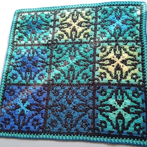 May include: A crocheted blanket with a geometric pattern in shades of blue, green, and black. The blanket is made up of repeating squares with a central star design.