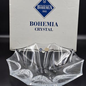 May include: A clear crystal bowl with a unique, scalloped edge design. The bowl is made by Bohemia Crystal and is displayed in front of its original box. The box features the Bohemia Crystal logo and the words "Bohemia Crystal."