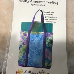 May include: A sewing pattern for a purple and blue tote bag with the title "Totally Awesome Toolbag" by Karen West. The pattern is from "For the Love of Fabric" and includes the website address www.lovethefabric.com.
