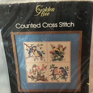 May include: A Golden Bee Counted Cross Stitch kit titled Birds Patchwork Picture. The packaging features a four-panel design of various birds on branches. It includes 100% cotton Aida cloth, floss, needle, and instructions for a 12 inch by 12 inch finished size.