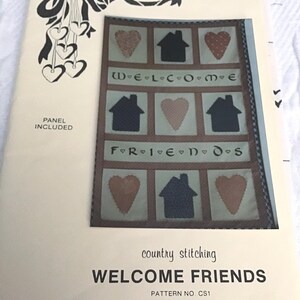 May include: A vintage sewing pattern for a quilt titled "Welcome Friends". The pattern features a quilt block with houses, hearts, and the words "Welcome" and "Friends". The pattern is from Country Heartstrings and is pattern number CS1.