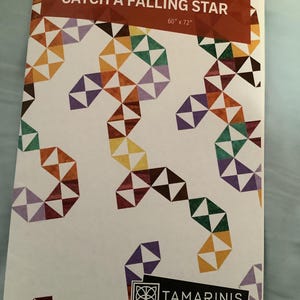 May include: A quilt pattern titled "CATCH A FALLING STAR" with a geometric design in shades of orange, yellow, green, purple, and brown. The pattern measures 60" x 72". The brand name "TAMARINIS" is also visible.