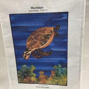 May include: A quilt pattern featuring a sea turtle swimming in blue water with coral reefs. The pattern is titled "Mortimer" and is for a quilt measuring 17.5 inches by 24.5 inches.
