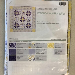 May include: A quilting kit for a Patience Wall Hanging, featuring a pattern and fabric pieces in shades of purple, white, and yellow. The finished project will be a 34-inch square.