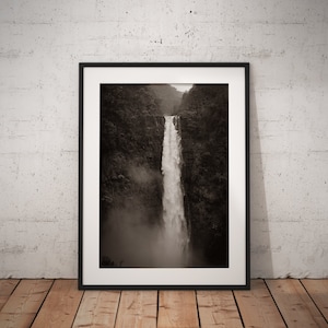 May include: A black and white photograph of a waterfall cascading down a rocky cliff face. The waterfall is surrounded by lush greenery and mist.