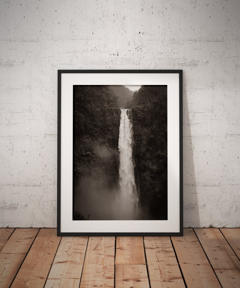May include: A black and white photograph of a waterfall cascading down a rocky cliff face. The waterfall is surrounded by lush greenery and mist.