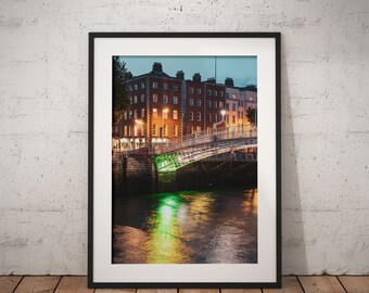 May include: A framed photograph of a bridge over a river in Dublin, Ireland. The bridge is lit up at night, and the reflection of the lights can be seen in the water. The buildings on the other side of the river are also lit up.