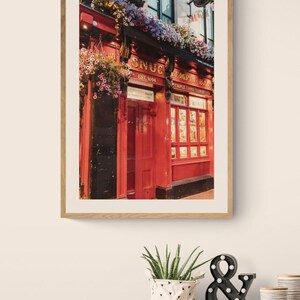 May include: A red brick building with a sign that reads "The Snug Temple Bar" and "Est. 1694". The building is decorated with hanging flower baskets and has a red door.