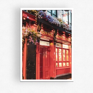 May include: A red brick building with a sign that reads "The Snug Est. 1894" and "Temple Bar" with hanging flower baskets.