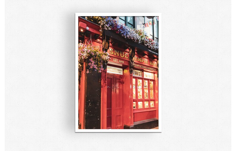 May include: A red brick building with a sign that reads "The Snug Est. 1894" and "Temple Bar" with hanging flower baskets.