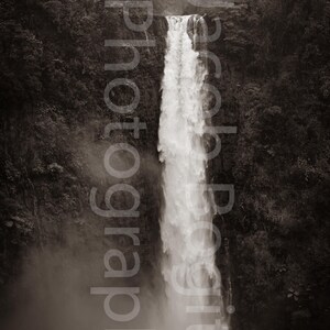 May include: A black and white photograph of a waterfall cascading down a steep cliff face. The waterfall is surrounded by lush greenery.